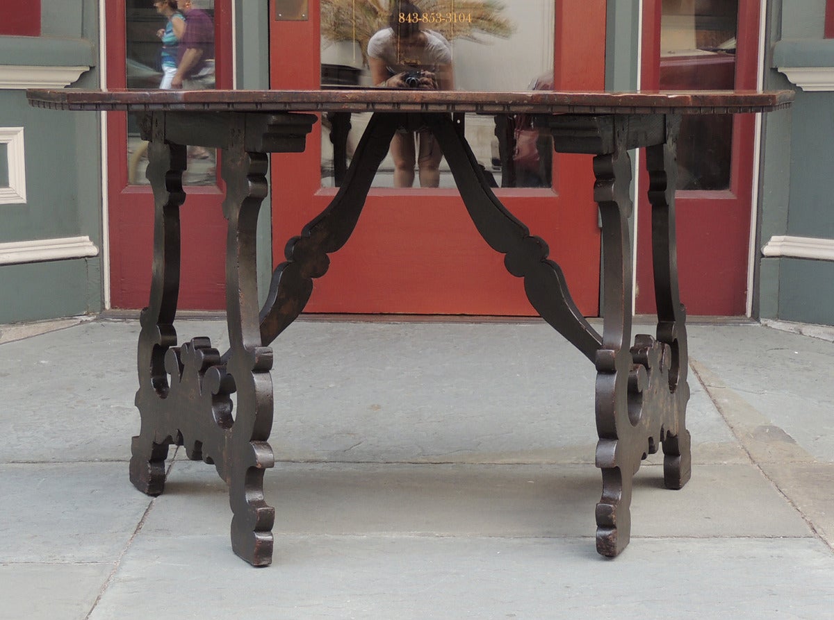 This pair of console tables was made in Italy during the late-17th to early-18th century. The consoles feature flat demilune-shaped wooden tops above two carved legs and stretchers. The legs are carved with a series of 'c' and 's' scrolls with
