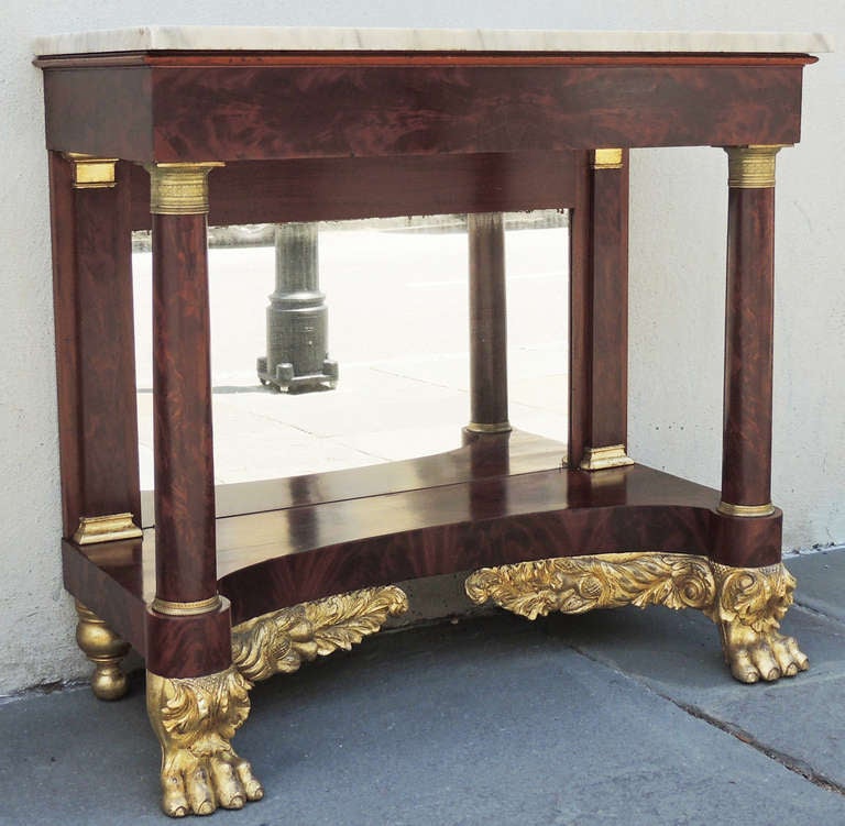 A 19th century New York marble-topped console with a mirrored back, gilt paw feet, and foliage decoration.
