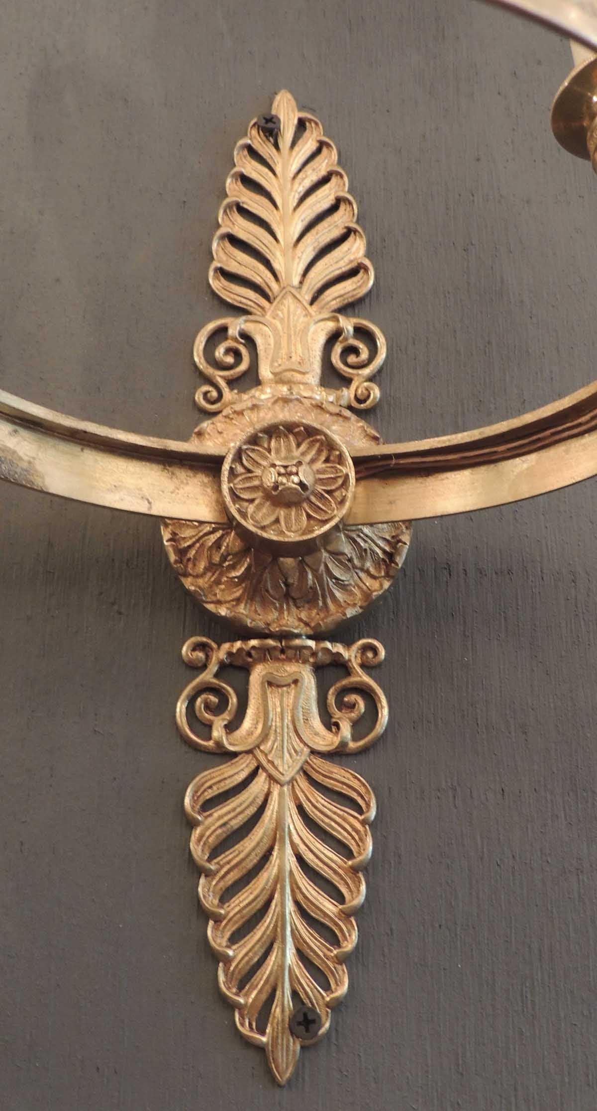 Ces appliques en bronze sont de style Second Empire et ont été créées en France, vers 1850. La paire comporte trois lumières montées sur un cercle à motifs. Les plaques murales de ces appliques comportent deux grands anthémons au-dessus et