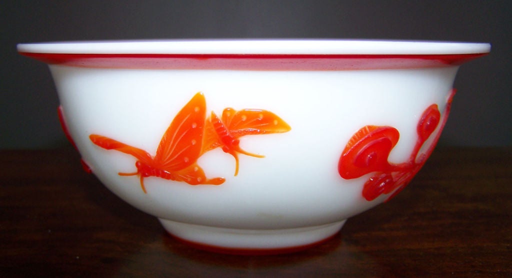 A vibrant Peking glass decorated with flowers and dragonflys.