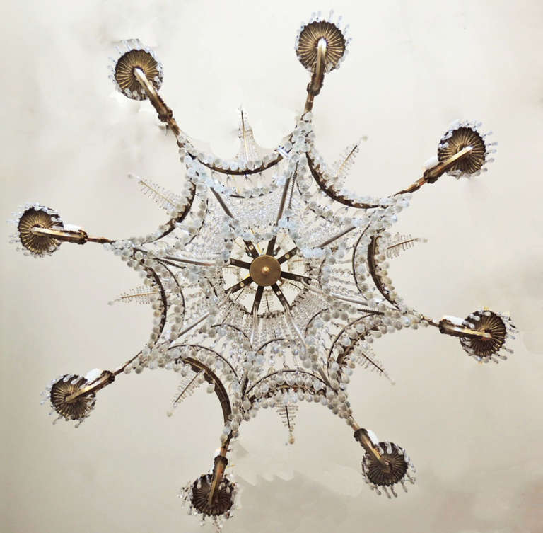 This elaborate chandelier, circa 1880, is made of bronze and crystal and features several different sizes of crystal ranging from long spears on the bottom to the beaded feather details on the body. The crown of the chandelier also features the