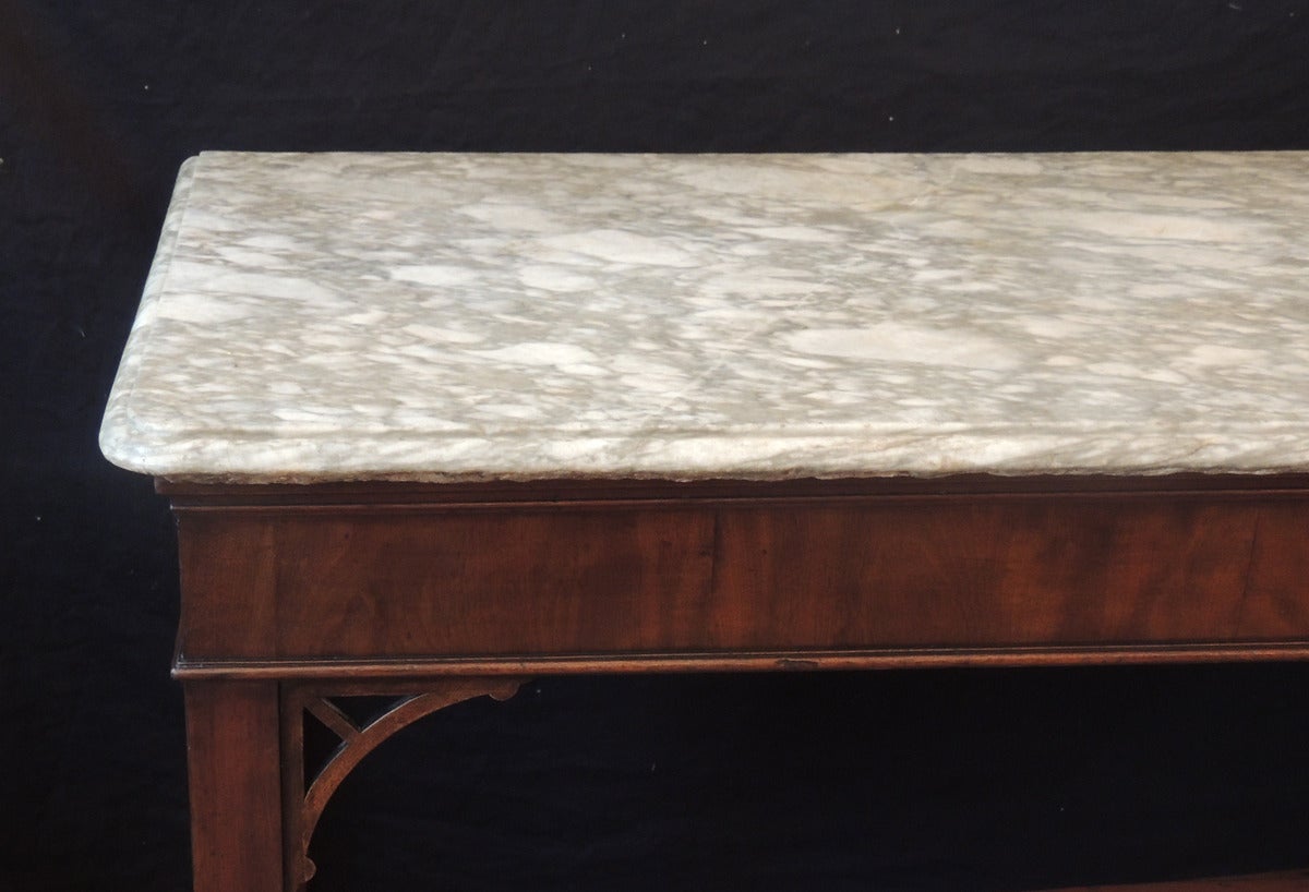 This English Chippendale style table was made in the mid-18th century, circa 1760 It has a mahogany body with Marlborough legs and simple open fretwork brackets. The tabletop is a massive piece of beautiful hand-chiseled, gray-veined marble, and is