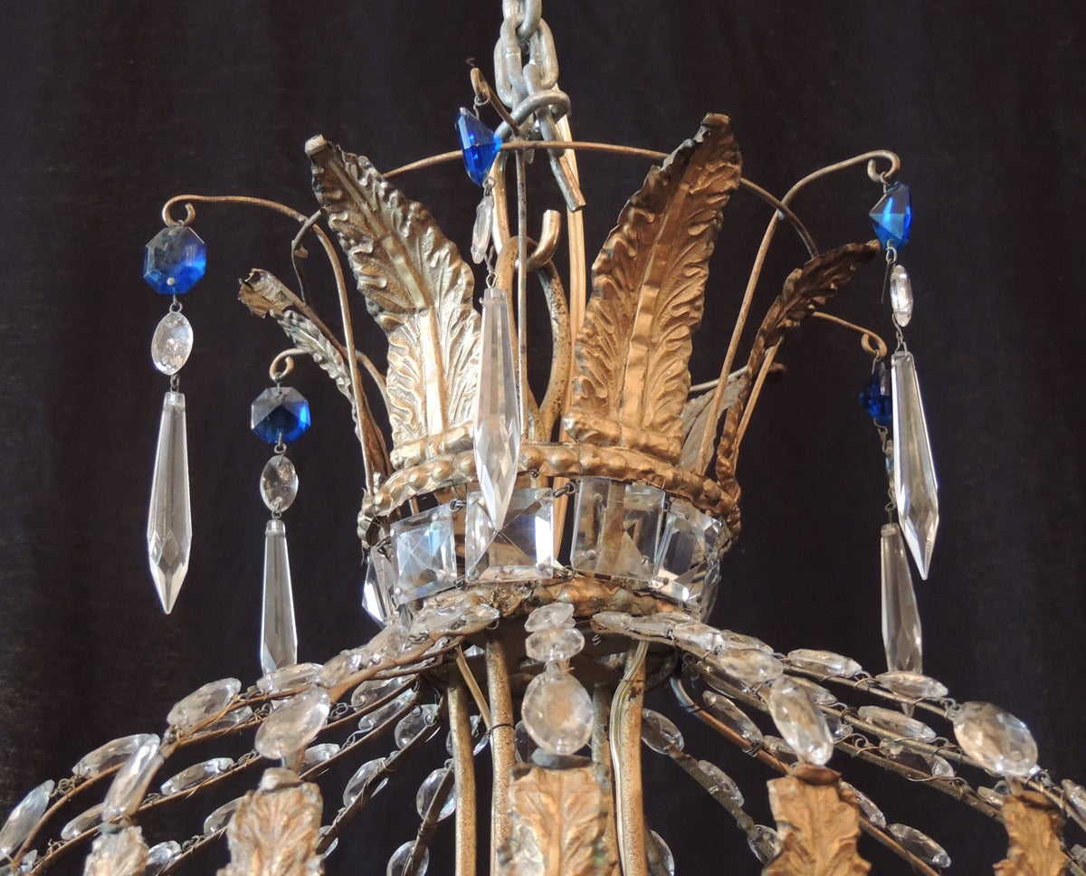 This chandelier was made in Italy during the late 18th century in the Moroccan style. The chandelier features a top crown with blue and clear crystals above a bulb-shaped section made with tole leaves and crystal chain. The body of the chandelier is