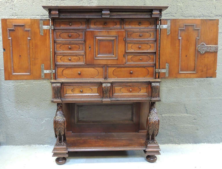 This magnificent Verguano Style piece is made of Walnut. Two grand outward doors open to feature nine small drawers and two larger drawers, along with a interior cabinet.  The stand features ball feet with hand carved eagles and two exterior drawers.