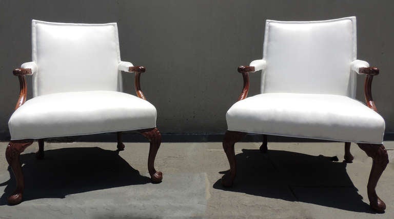 This pair of arm chairs are in pristine condition with newly restored upholstery. The wood carving on the arms and legs feature beautiful vertical acanthus leaves. The base of the arm on either side feature a gorgeous hand carved shell design. This