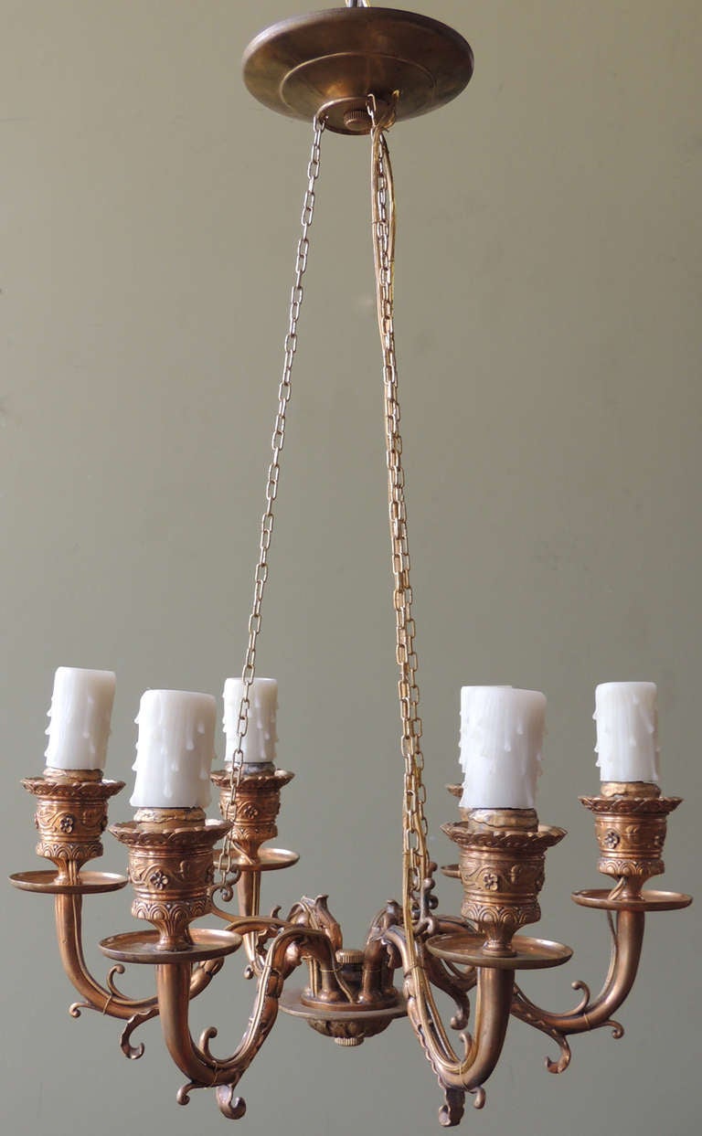 This 1840's French bronze chandelier was originally constructed for candles, but has been wired for electricity. The base and arms feature scroll like designs typical to the European Rococo-Revival period.

