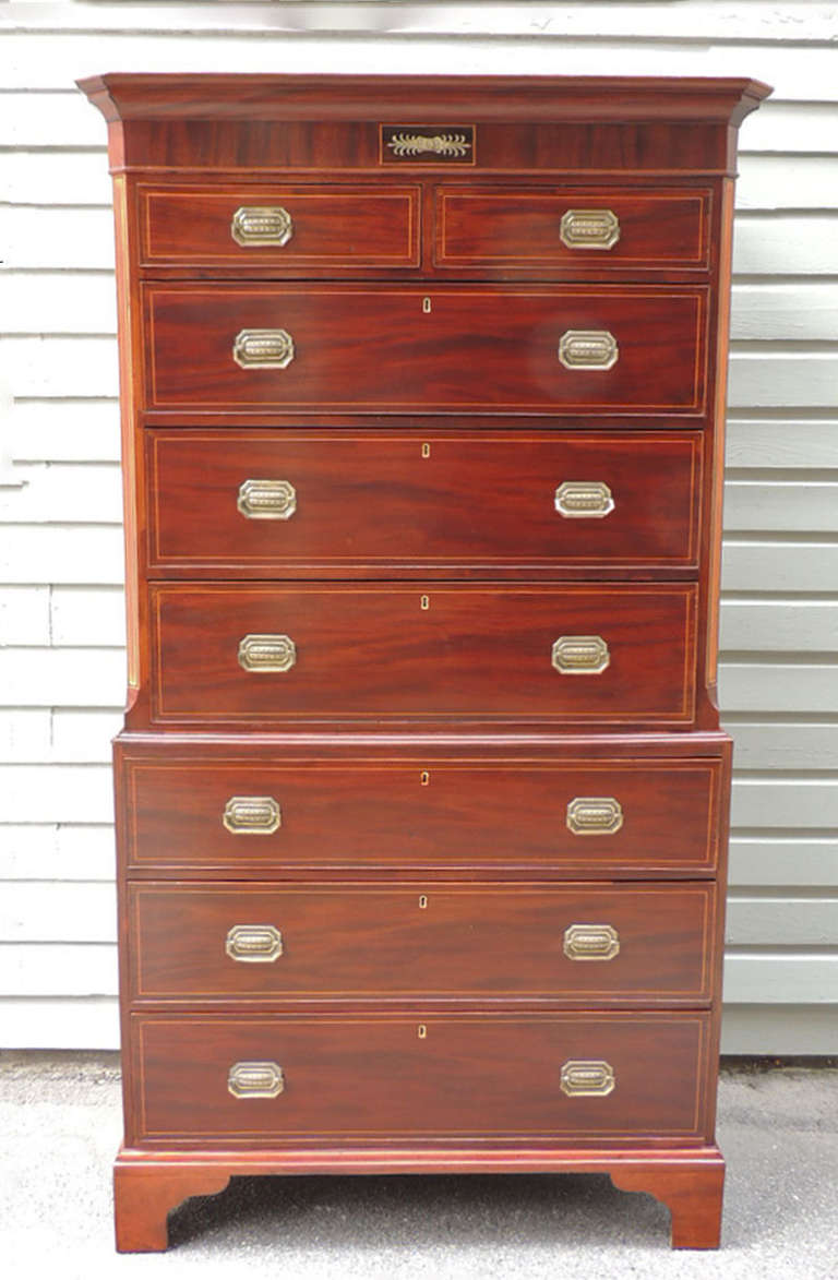 This piece was made in England during the 18th century and is made of mahogany with pine secondary. This piece has three sections with three large, three medium, and two small drawers. The top features gold inlay. The bottom has bracket feet.