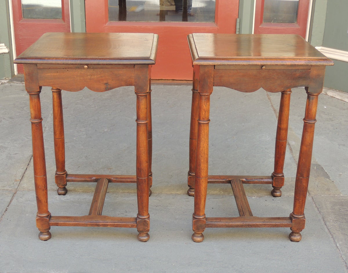 These Directoire walnut candle stands / work tables are excellent examples of French Provincial furniture. Each of tables have a flat surface sitting on ogee curved aprons with a pull-out writing slide and four turned legs. The base of the tables