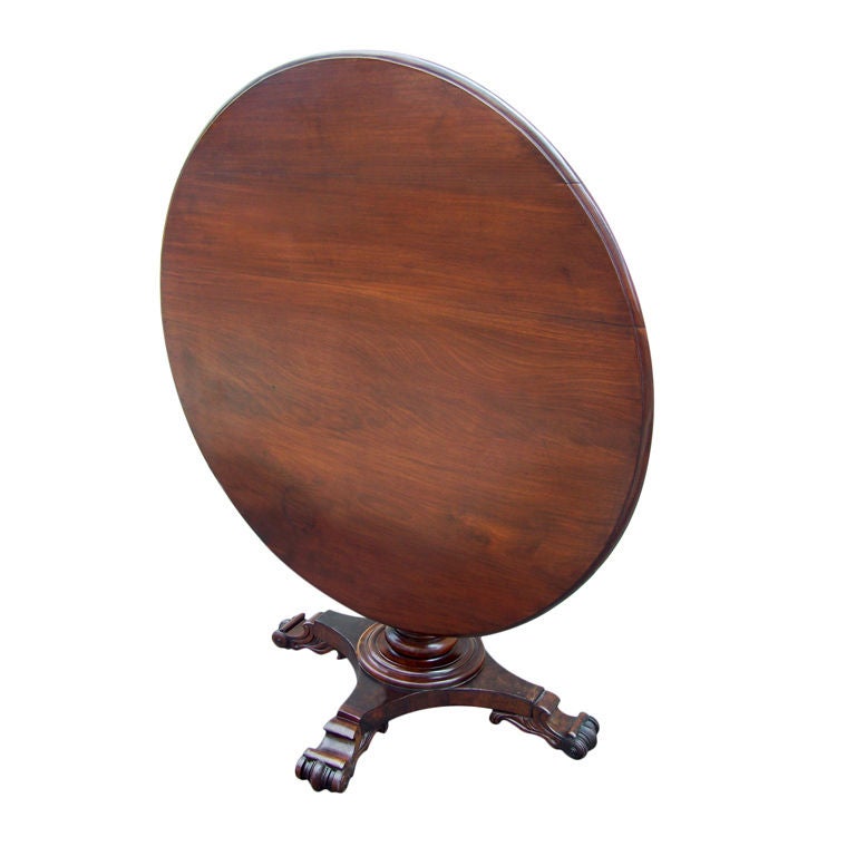 A 19th century mahogany Caribbean tilt-top center or dining table featuring a West Indies turned and carved pedestal and carved feet.