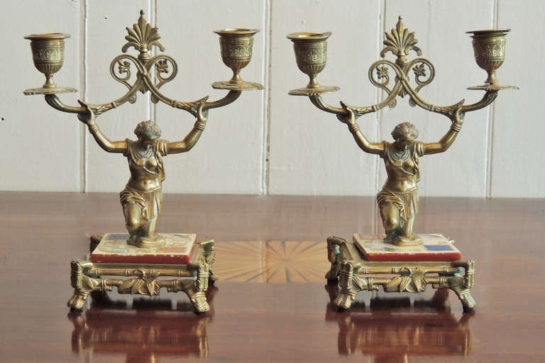 This pair of English Regency candlesticks were made circa 1820 and are constructed of bronze with detailed etching and casting. Each candlestick has two arms supported by kneeling women. The bases are made of porcelain.