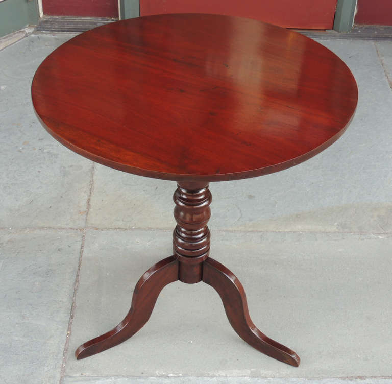 This Caribbean British Colonial tea table was made in the early-19th century, circa 1830. This West Indies table features a circular surface with a hand-turned center post on a three leg pedestal base with snake feet.