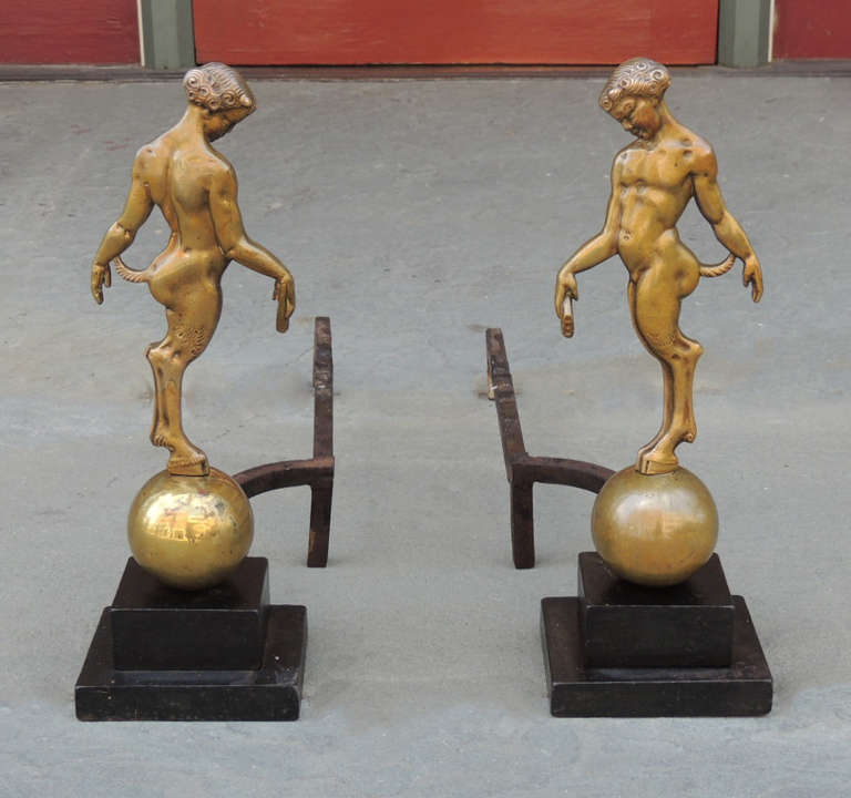 This pair of andirons was made in France during the first half of the 19th Century, circa 1900. This pair features bronze fauns standing atop spheres. The bases of this pair are iron.