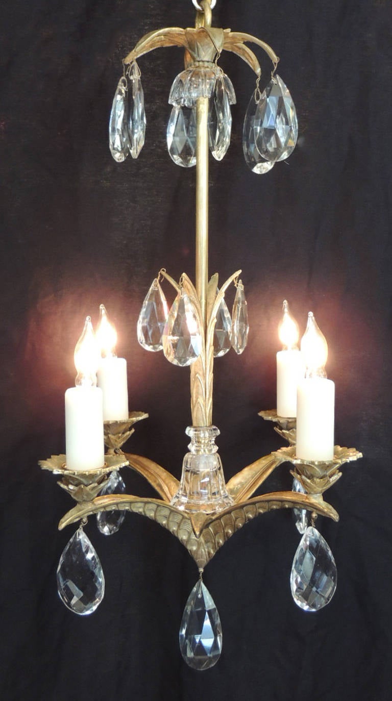 This Art Deco chandelier was made in France during the first half of the 20th century, circa 1920. This chandelier has a central stem with foliate details on the bottom near the arms. There are four hand-hammered arms that resemble palm branches.