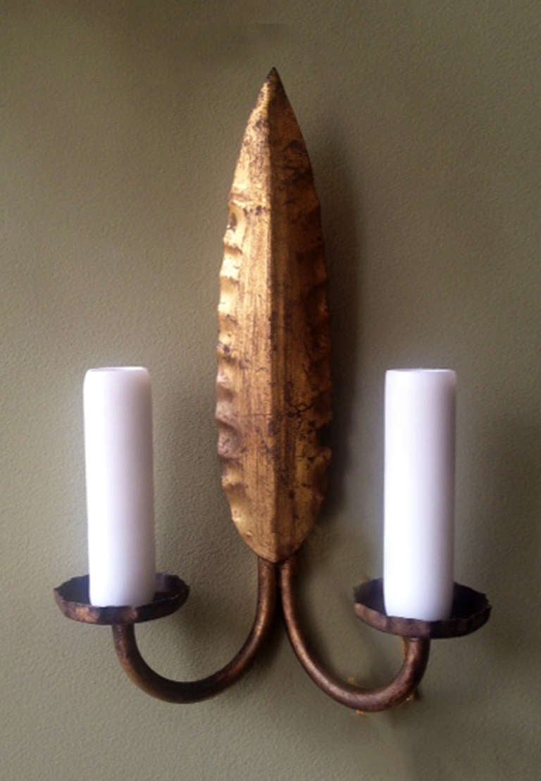 This beautiful pair of sconces was made in Barcelona in the 1950's. Each piece features a feather or leaf shaped body and two candle arms. Each of the arms support candelabra bulbs and have porcelain sockets.