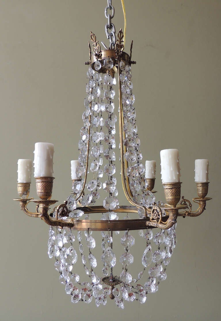 This brass and crystal chandelier was made in England in the 1790s. The oval shaped crystals line the top of the piece and come into a basket shape towards the bottom. The chandelier originally held candles but has been French wired to accommodate