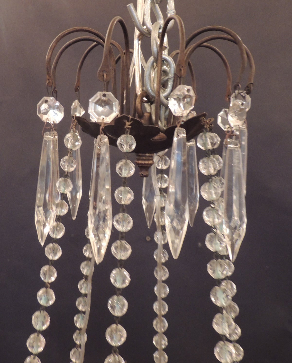 This Italian Neoclassical chandelier was made in the mid-19th century, circa 1850, and features crystal prisms at the top surrounded by four crystal chains that suspend the bottom of the chandelier. The bottom section of the chandelier had six