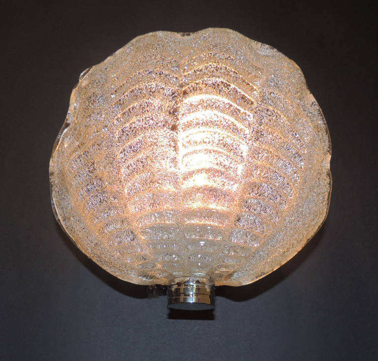 This set of ten identical sconces were made in Italy on the Venetian islands of Murano. The sconces are each in the shape of a cockle shell and defined ridges and reeded chrome bases.