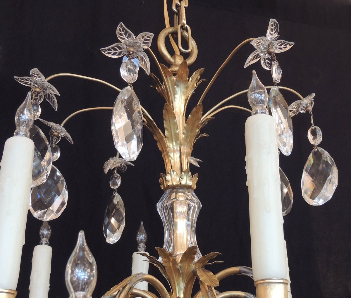 This beautiful chandelier was made in France in the early half of the 20th century, circa 1920. This piece features bronze foliage at the top with crystal flowers and prisms that are attached to and bronze and crystal center section. There are two