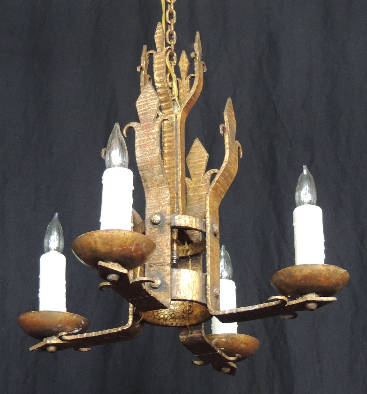 This chandelier was made in Barcelona, Spain in the early 20th century, circa 1910. It was made to reflect a Mediterranean style with Prince of Wales plumes at the top and center of the chandelier. The piece has four arms that have been recently