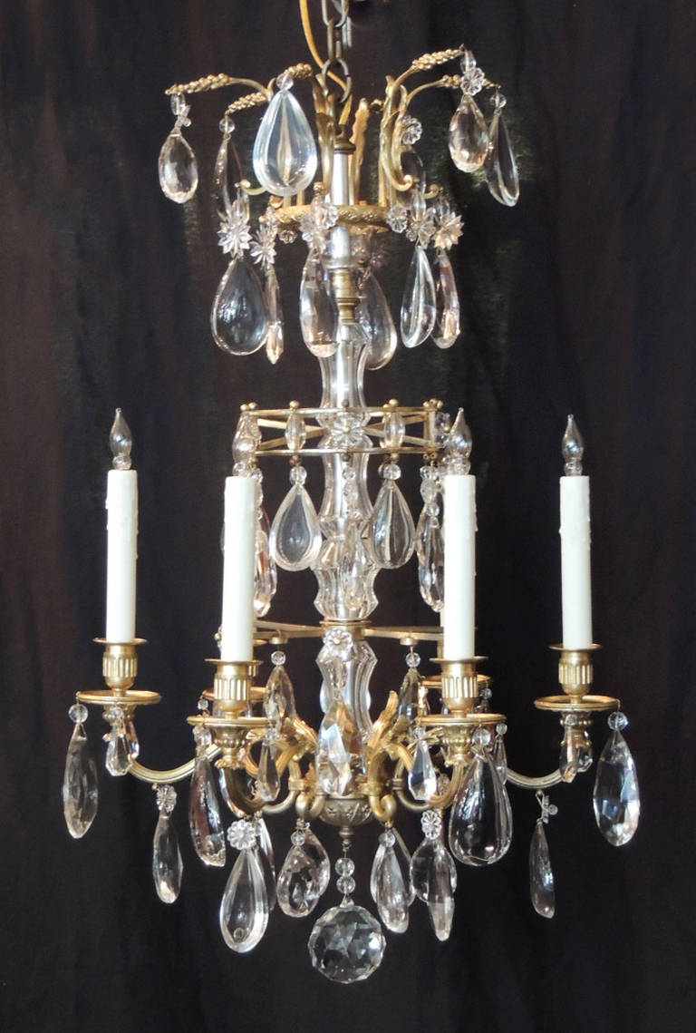 This chandelier was made in France during the first half of the 20th century, circa 1920, and is attributed to Maison Jansen. The top of this chandelier has six small bronze arms adorned with crystal prisms and rosettes. The central rod of the piece
