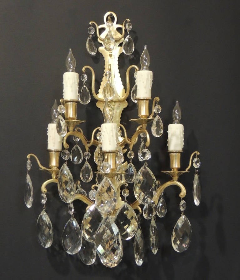 This pair of sconces was made in France during the mid-19th century, circa 1850. These sconces feature five lights each with scroll details on the arms and crystal drops of varying sizes. This pair was originally made for candles but has been wired