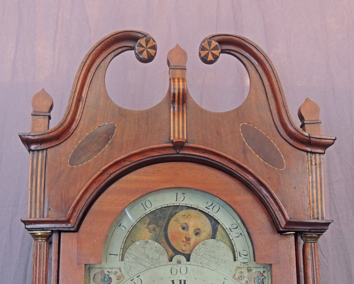 This magnificent American grandfather clock was made in New Jersey, circa 1790 and retains its original paper label that bears the maker's name, John Scudder. The grandfather clock features federal style inlay with a top broken cornice with pinwheel