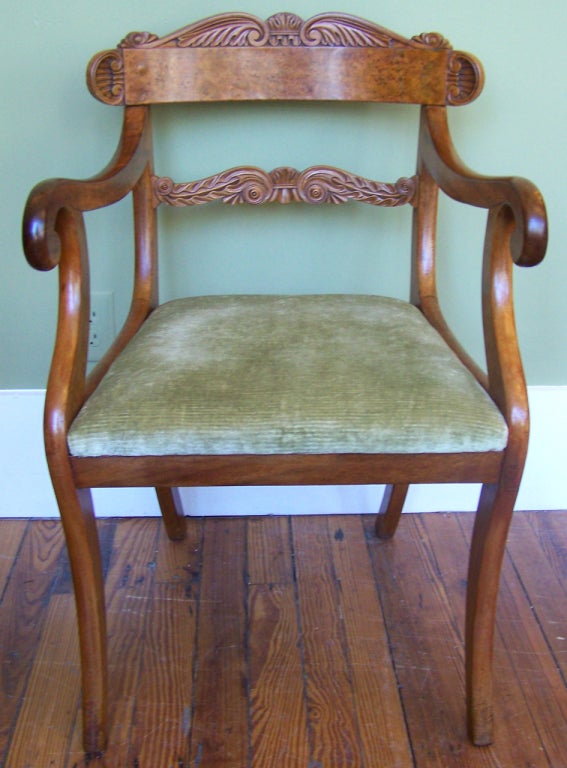 A early-19th century pair of English Regency armchairs. The crest and back rail have scrolled acanthus leaves. The other details of these chairs include curving arms and sabre legs and are signed by S. Jamar. 