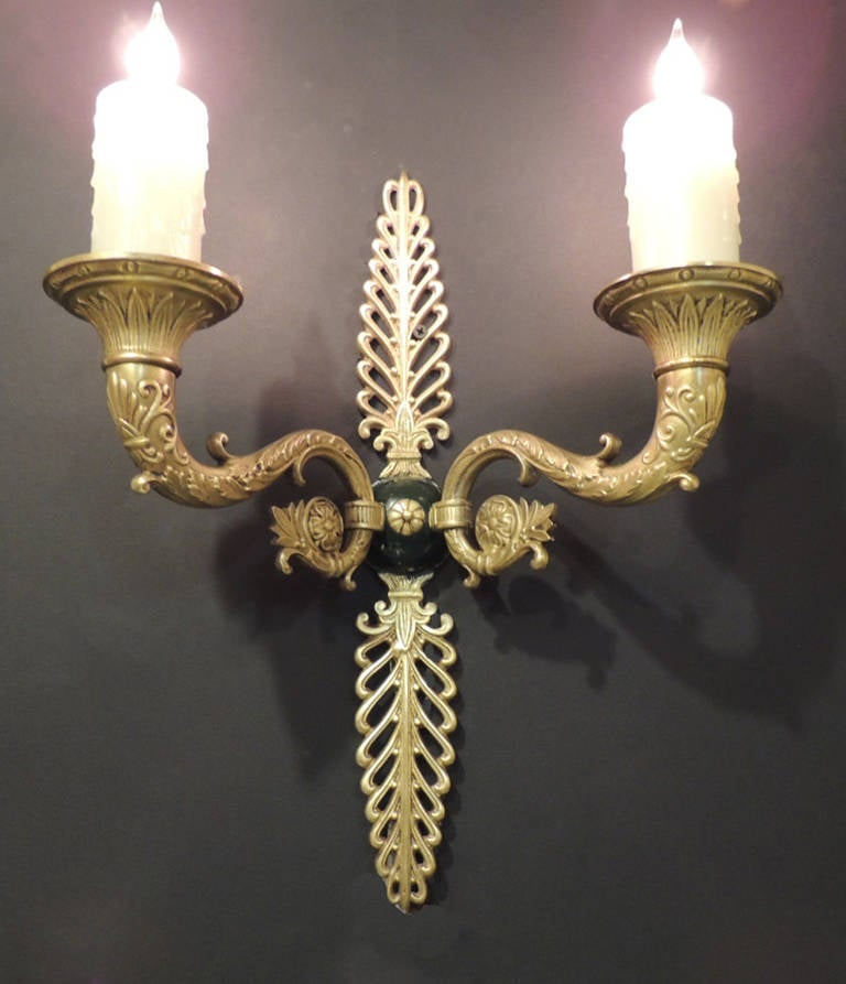 This pair of sconces was made in France in the late-19th century, circa 1890, and feature anthemions above and below a verdigris circle in the middle. The two arms are of cast bronze with scroll and palm details. They were originally gas-burning but
