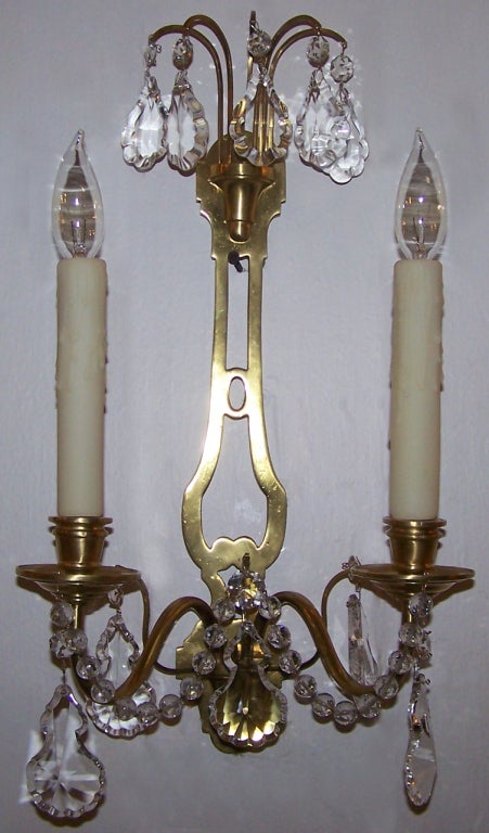 A 20th century pair of French Directoire style sconces dating from the 1920s. Each sconce has two arms and dainty crystal swags and prisms.