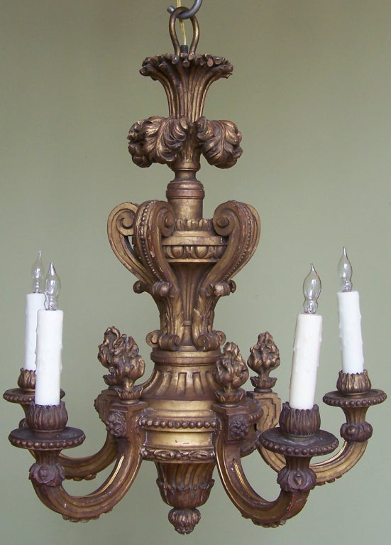 Italienischer Goldholz-Kronleuchter aus dem frühen 20. Jahrhundert. Fünfflammige Arme mit flammenden Urnen, eleganten geschnitzten Schnörkeln und einer Akanthusfahne auf der Spitze.
