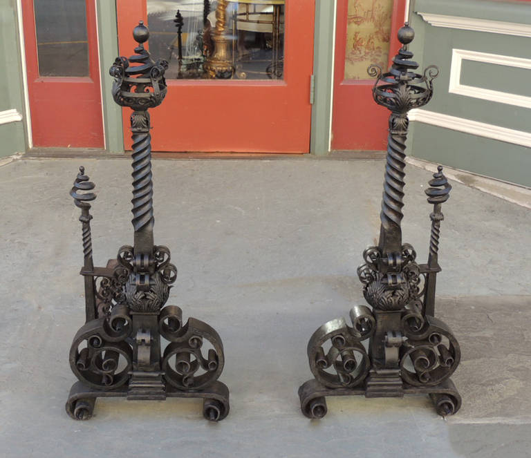 This pair of andirons was made in America during the late 19th century, circa 1860. This pair was hand-hammered and hand twisted to get its unique look. The bottom features scrolled bases with turned stems topped with decorative finials.