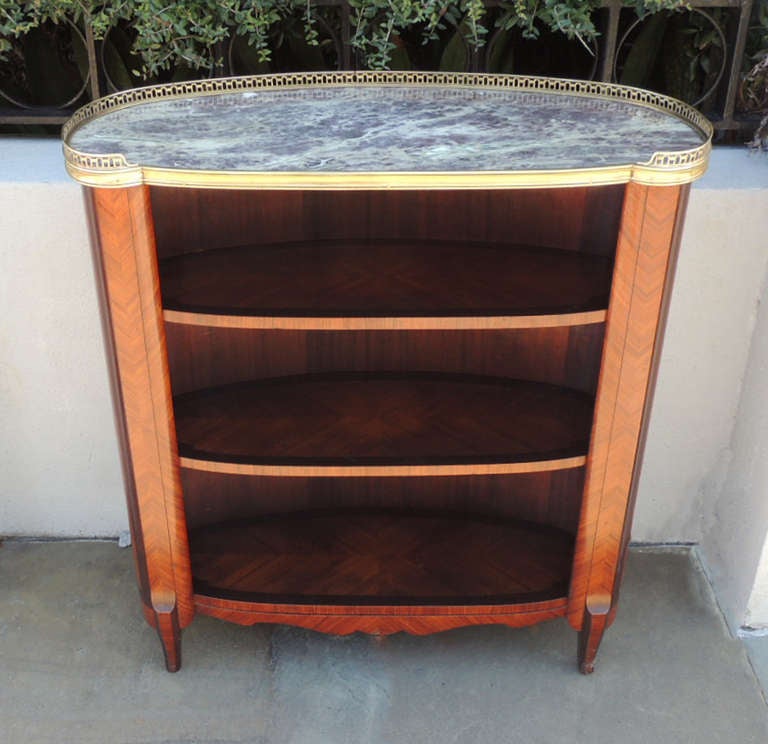 This finished piece is made of solid kingwood with bronze details around a marble top. This piece has three removable shelves. The bottom of this case features a decorated skirt and tapered legs. 