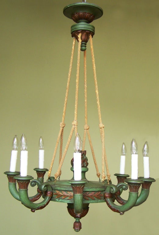 A charming Italian Empire style eight-light chandelier, circa 1920, with green painted and carved wood frame suspended with rope cording.