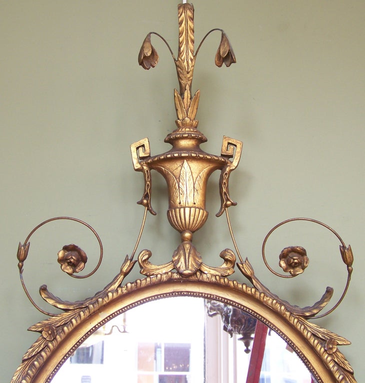 A beautiful early 20th century Adams style giltwood mirror. This mirror features girandole arms, beautiful carving and an urn feature on top.