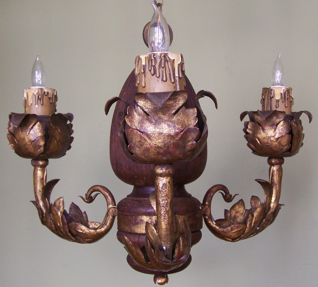 An early 20th century Italian chandelier, circa 1920, with carved wood acorn shaped center and three foliate gilt tole candle arms.  