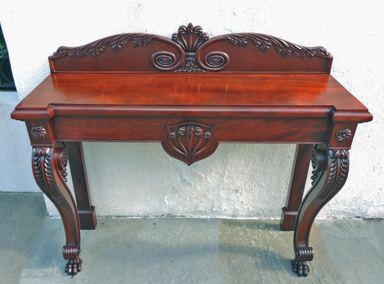 This console table is made of mahogany and is intricately carved on the top and bottom of the piece.