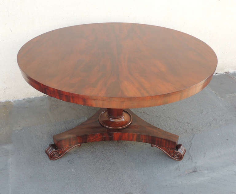 The beautiful table is made of cedrela with a mahogany veneer. The circular top is able to be tilted to be easily stored. When folded down the top sits on a tripod base with hand-carved claw feet. Additionally, surrounding the feet are scrolls to