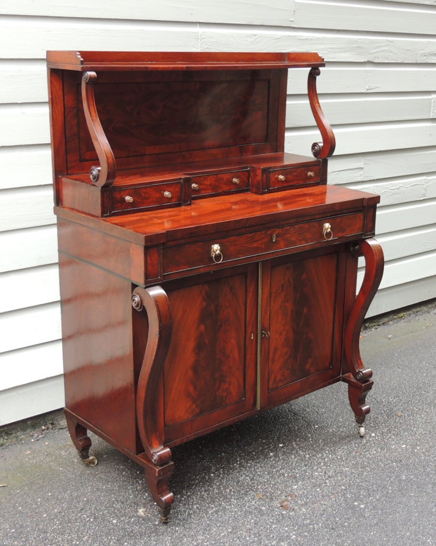 This elegant and useful credenza was made in England, circa 1805, and features three small drawers, one large drawer and a cabinet below. The hardware is gilt lion pulls and casters that are original to the piece.