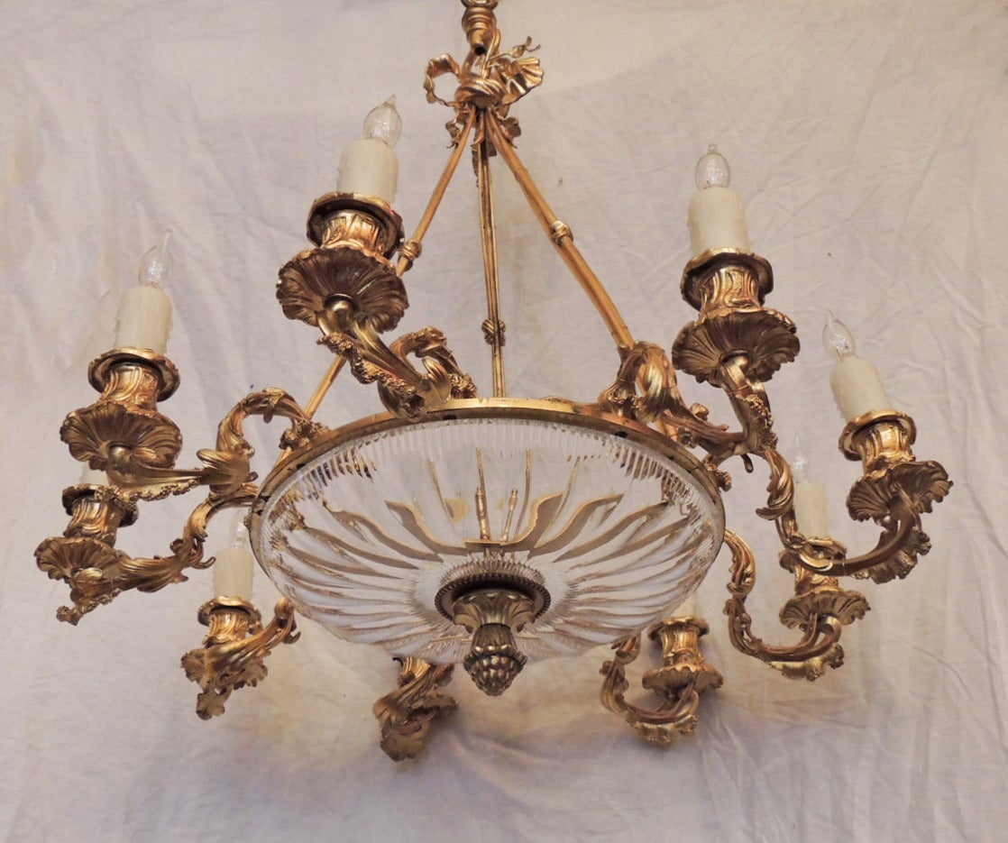 This chandelier was made in France during the first half of the 19th century, circa 1810, and features a crystal fluted bowl and nine elaborate foliate arms. The base of the bowl is accented by an acorn-shaped finial. The fixture has been rewired