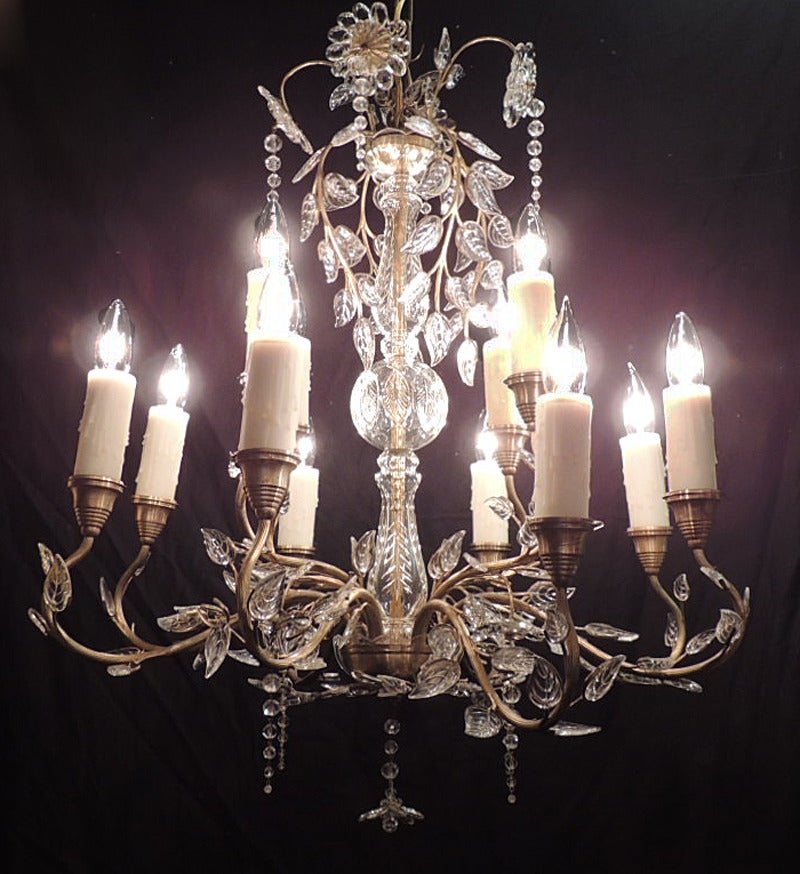 This chandelier was made in Germany in the 20th century in the Maison Bagues style. The top of the piece features a crystal floral arrangement above  cut crystal leaves. The body of the chandelier is bronze with a crystal bulb and surround. The arms