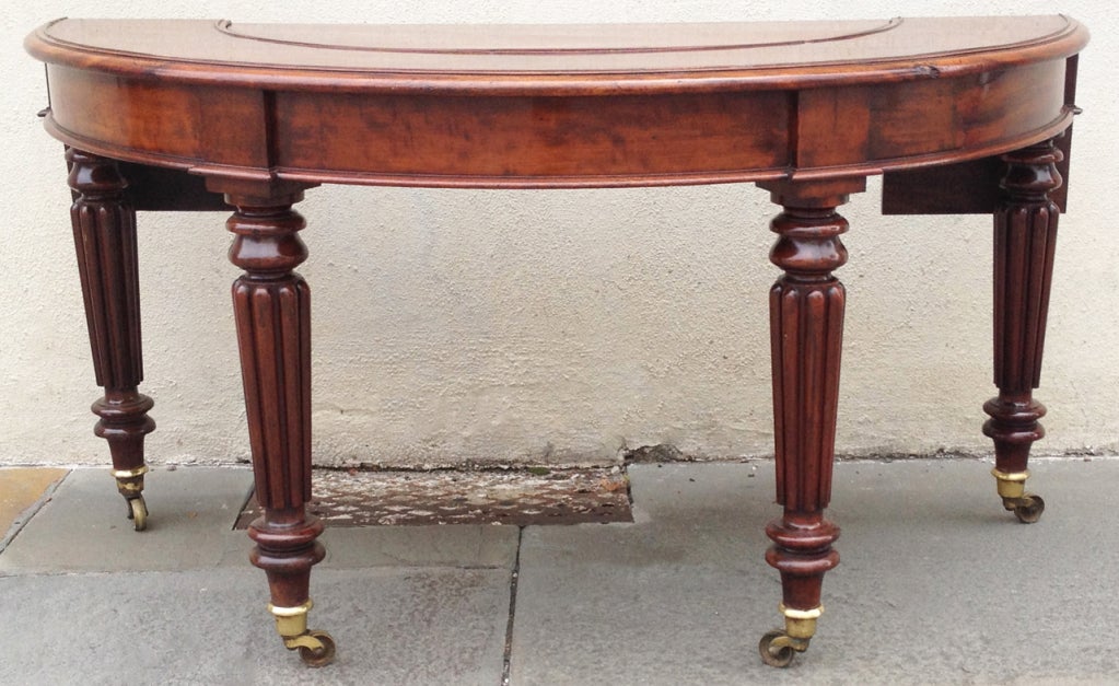 A rare style, this 1820s Regency social/hunt table features the distinct half-moon shape of the social table, complete with extendable ends, removable center piece, and four cant carved and fluted legs. A unique and beautiful piece.