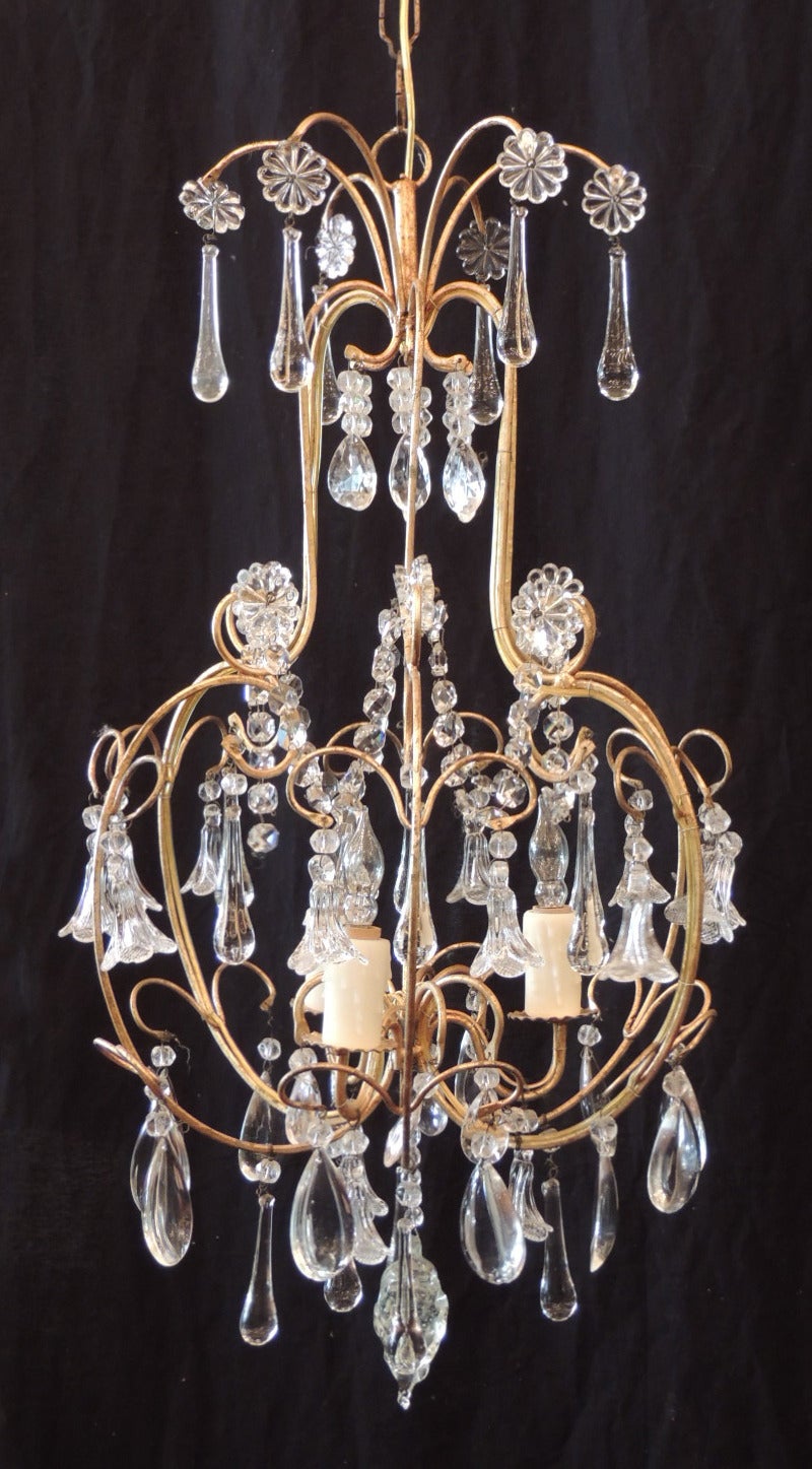 This chandelier was made in Italy during the mid-20th century, circa 1960. The body is elegantly shaped and features handblown crystal rosettes and crystal prisms on each top stem. The body has floral and French drop crystals with crystal swags.