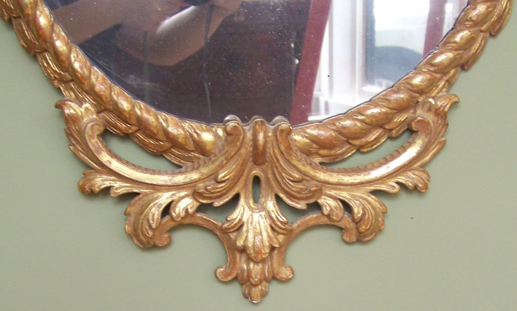 A lovely late 18th century English oval mirror. Wonderful carving on crest, and elegant rope motif.