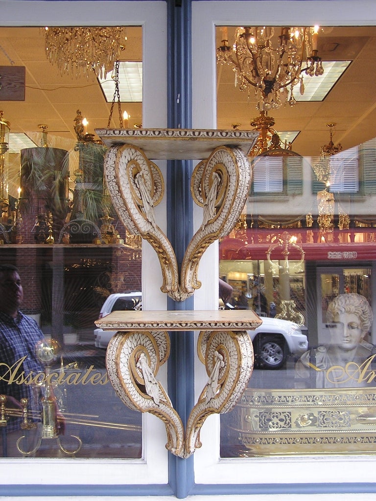 Pair of Italian carved wood painted and gilt wall brackets with scrolled floral and tassel arms supporting upper shelf. Early 19th Century