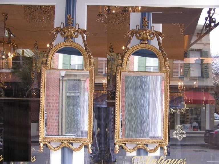 Pair of French gilt carved wood and gesso wall mirrors with centered urns, graduated bell flowers and decorative foliage swags. Late 18th Century.  Mirrors retain the original glass and wood backing. 