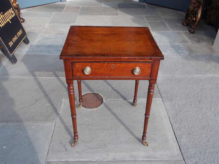 English Regency mahogany one drawer work table with tulip wood cross banding, fitted leather interior desk, original brass pulls, and terminating on turned bulbous legs with original brass casters. Early 19th Century