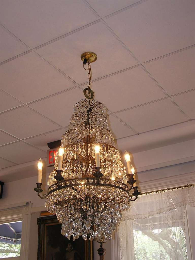 Pair of French tiered bronze and crystal eight light chandeliers with  floral motif. Originally candle powered and has been electrified.  Circa 1820.