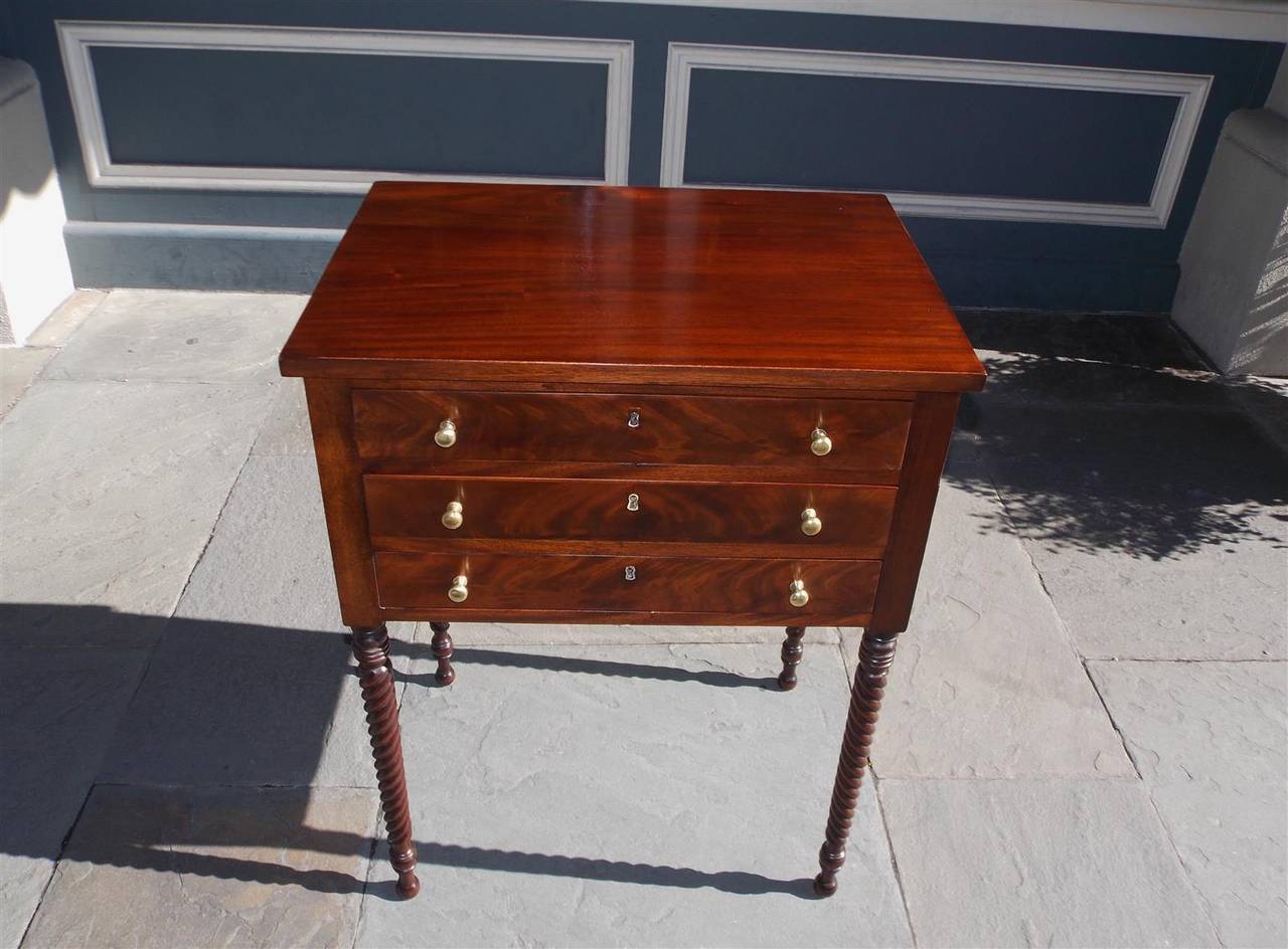 American Sheraton crotch mahogany three drawer work / side table with original brass knobs, and terminating on turned bulbous barley twist legs.  Early 19th Century