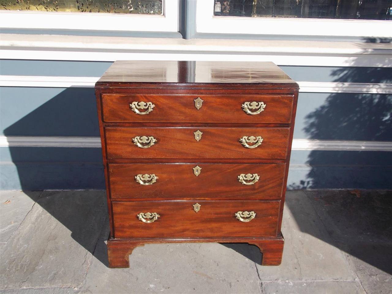 English Chippendale mahogany graduated four-drawer bachelors chest with original brasses, side handles and bracket feet, Late 18th century.