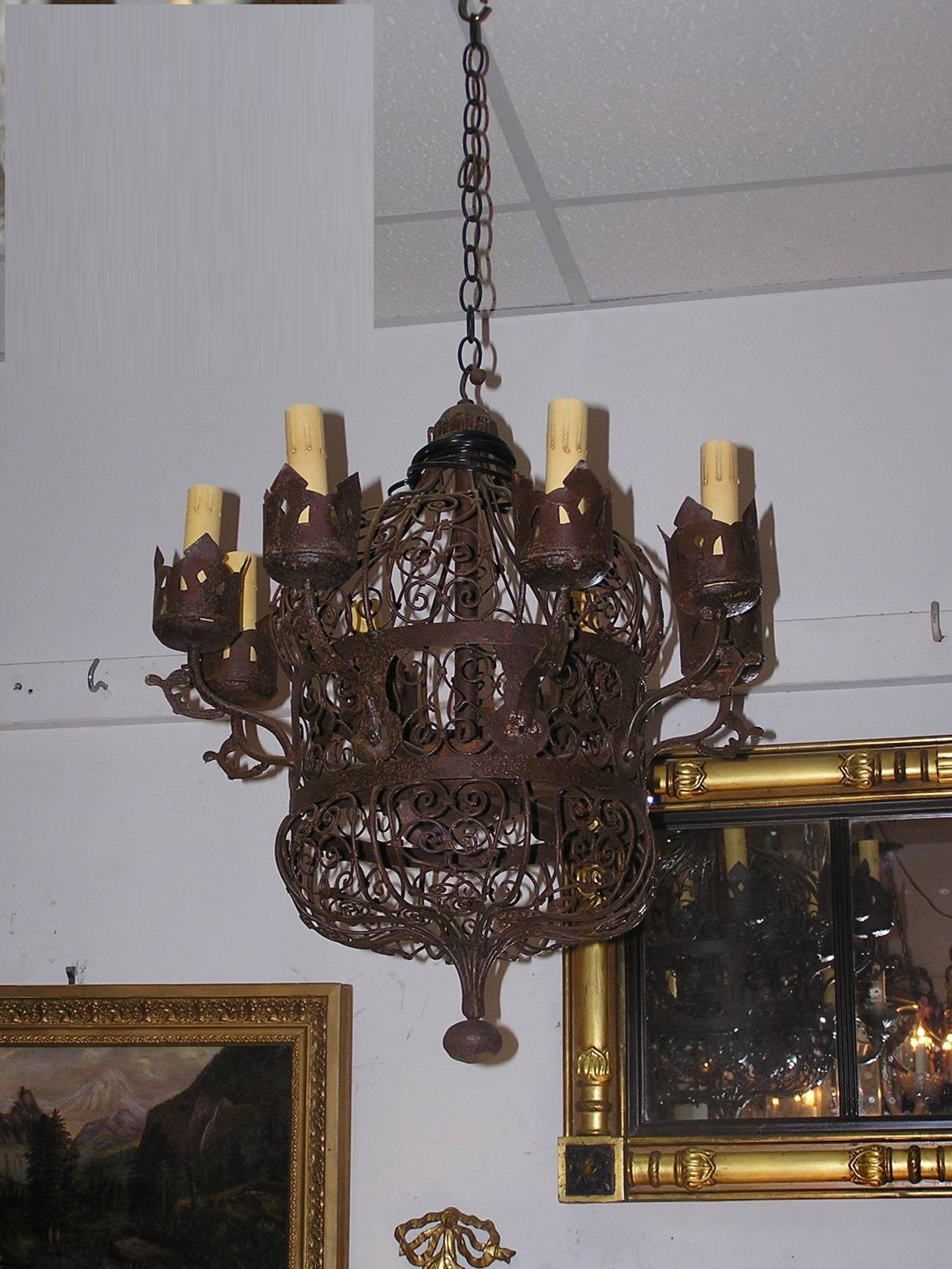 Lustre américain en fer forgé à huit lumières, avec un travail décoratif en fil de fer à volutes, des bobaches décoratives percées, et se terminant par une boule de fer conique centrée.  Milieu du XIXe siècle.  Le lustre était à l'origine à gaz et a